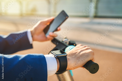 Close up of young business guy using cellphone rental of eco transportation at city street. Businessman unlocking in mobile application e-transport