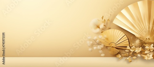 A Japanese golden fan rests next to a vibrant bouquet of flowers on a wooden table. The fan is partially opened  revealing intricate designs  while the flowers add a pop of color to the scene.