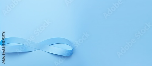 A white ribbon is displayed on a deep blue wall, symbolizing prostate cancer awareness. The ribbon stands out against the wall, creating a striking visual contrast.