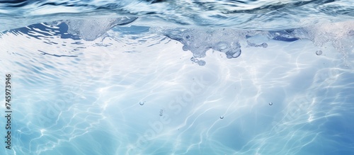 The water in the image is incredibly clear and blue, reflecting the sky above. The surface shows ripples and splashes, creating a serene and refreshing scene.