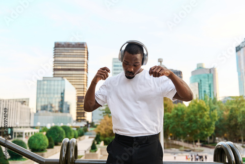 stylish young african american man listening to music with headphones outdoors and dancing photo