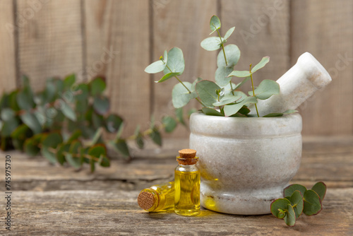 Eucalyptus leaves and mortar on a wooden background.Spa concept.Ingredients for alternative medicine and natural cosmetics. A bottle of essential oil and a bunch of eucalyptus. Organic skin care 