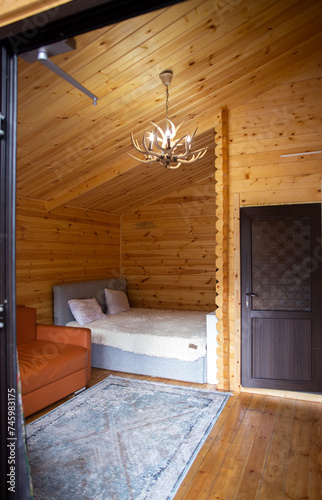 Rustic wooden cabin interior with bed, sofa, and armoire © abramov_jora
