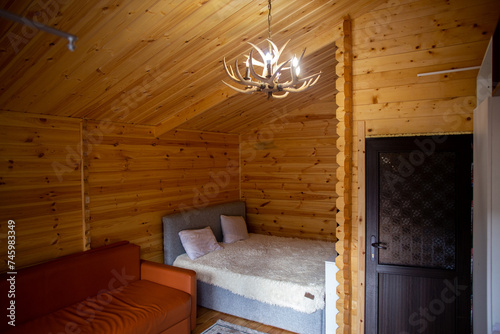 Rustic wooden cabin interior with bed, sofa, and armoire