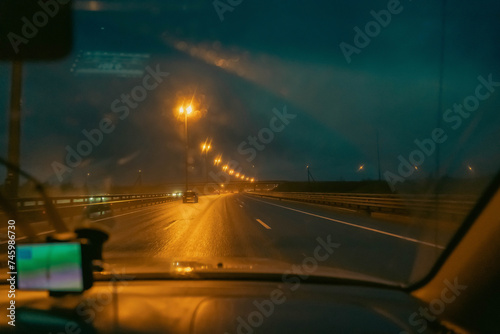 view of the night highway through the windshield of a driving car