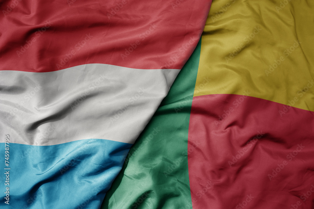 big waving national colorful flag of benin and national flag of luxembourg . big waving national colorful flag of benin and national flag of luxembourg .