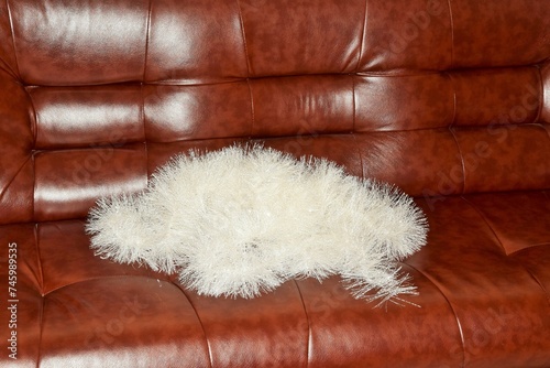 A white garland for decorating a fir tree lies on a leather sofa photo