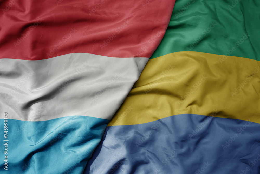 big waving national colorful flag of gabon and national flag of luxembourg . big waving national colorful flag of gabon and national flag of luxembourg .