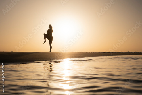 Mujer haciendo estiramientos en la orilla del Océano