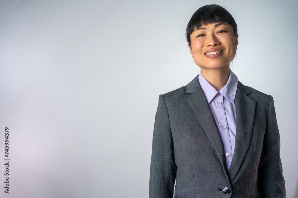 Portrait of a Japanese attractive business woman. Happy business woman posing isolated over grey wall background. Portrait of smiling Asian business woman, isolated on grey background. Portrait of a Japanese attractive business woman. Happy business woman posing isolated over grey wall background. Portrait of smiling Asian business woman, isolated on grey background.