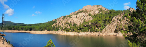 Near Porto-Vecchio, in the heart of Alta Rocca, Lake U Spidali is nestled between road and mountains. Due to the drought, the water level has dropped, revealing tree stumps cut before impoundment photo