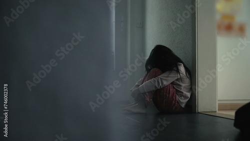 Child Struggling with Mental Illness in Childhood, Seated in Dark Home Corridor Covering Face in Anxiety