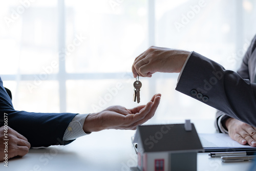Real estate agent handing over house keys to client. Home ownership and real estate transaction concept. photo
