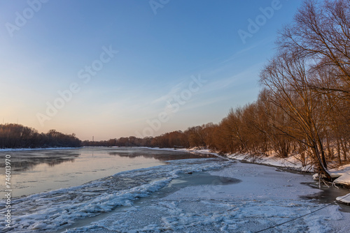 Ice floats on the water, frosty evening, cold, winter landscape with a wide river. © Sergei