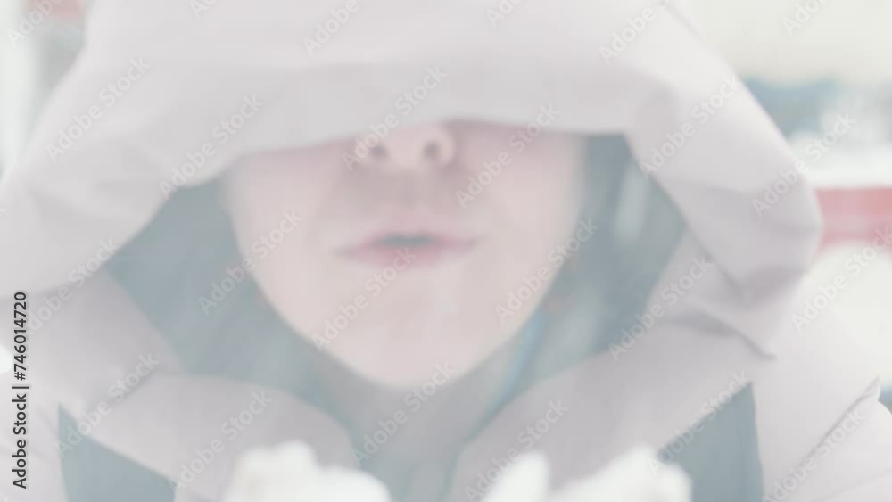 Winter caucasian girl in the hood blowing on the snow in her hands. Winter caucasian girl in the hood blowing on the snow in her hands.