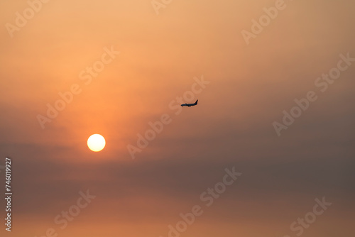 View of the sunset with a flying airplane