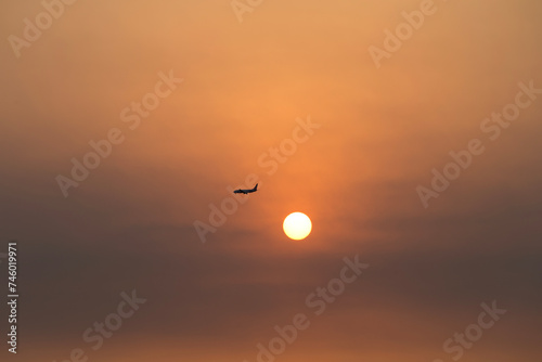 View of the sunset with a flying airplane