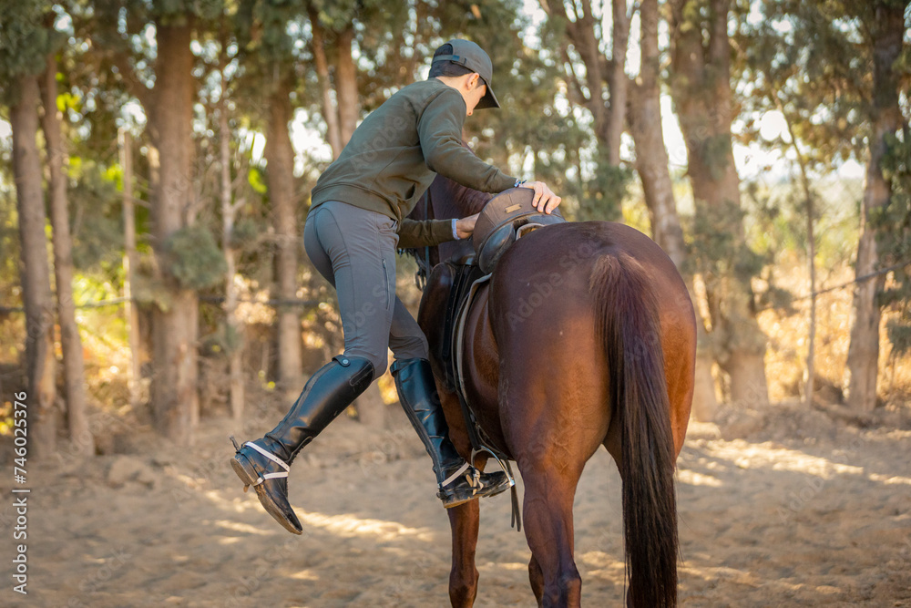 Fototapeta premium chico joven adolescente con gorra montando a caballo 