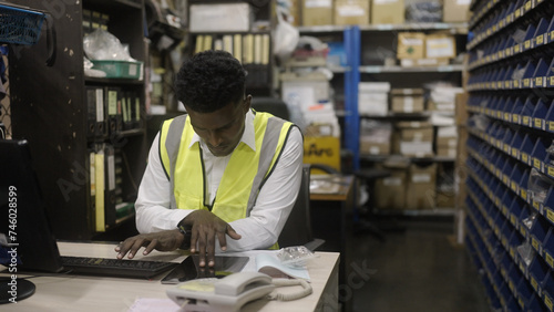 Black worker is checking the goods in the warehouse.