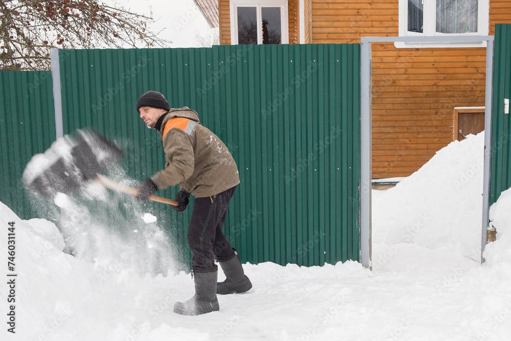 A European man removes snow in front of the gate of the house. A European man removes snow in front of the gate of the house.