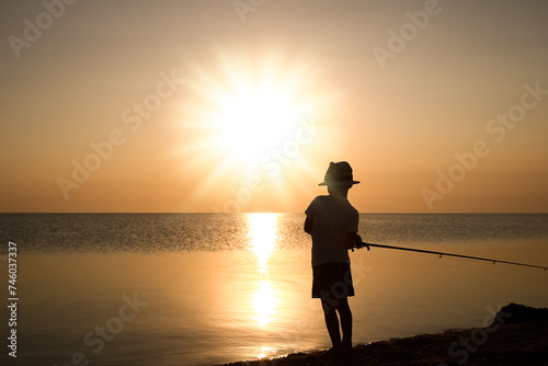 A Happy child fisherman fishing by the sea on nature silhouette travel