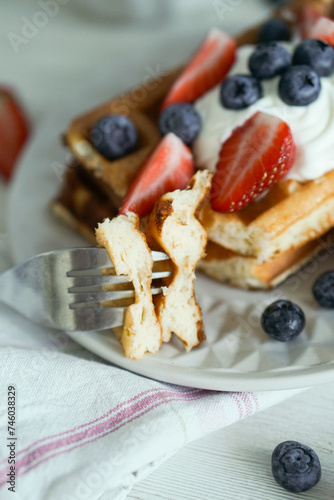 Home made waffles with whipped cream on top and fresh strawberries and blueberries perfect for breakfast close up selective focus