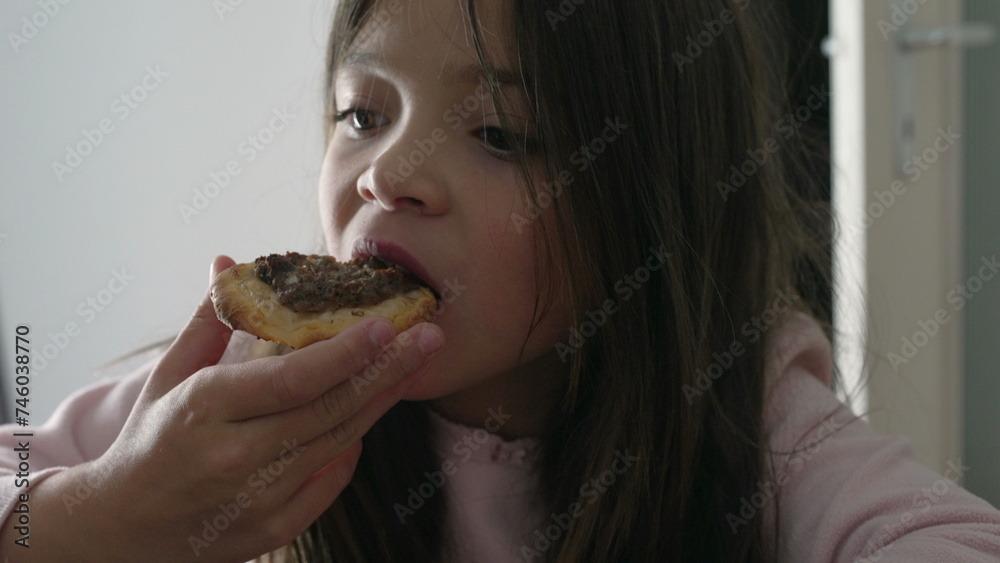One small girl snacking esfiha, traditional Arabic Brazilian food. Pastry filled with meat One small girl snacking esfiha, traditional Arabic Brazilian food. Pastry filled with meat