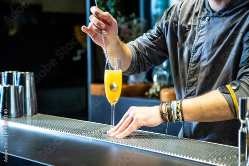 Barman prepara cokctail mimosa sobre la barra de un cocktail bar nocturno exclusivo muy delicioso © Alex