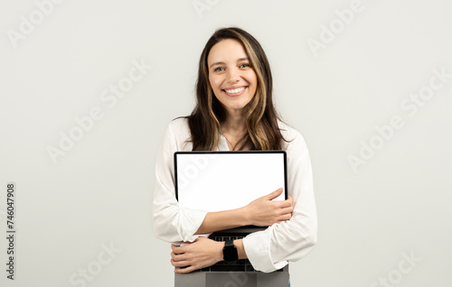 Happy woman embracing a laptop with a blank screen, dressed in a white blouse