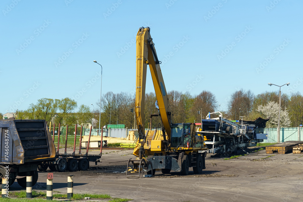 A yellow mobile crane works in a parking lot on a sunny day. Close-up.