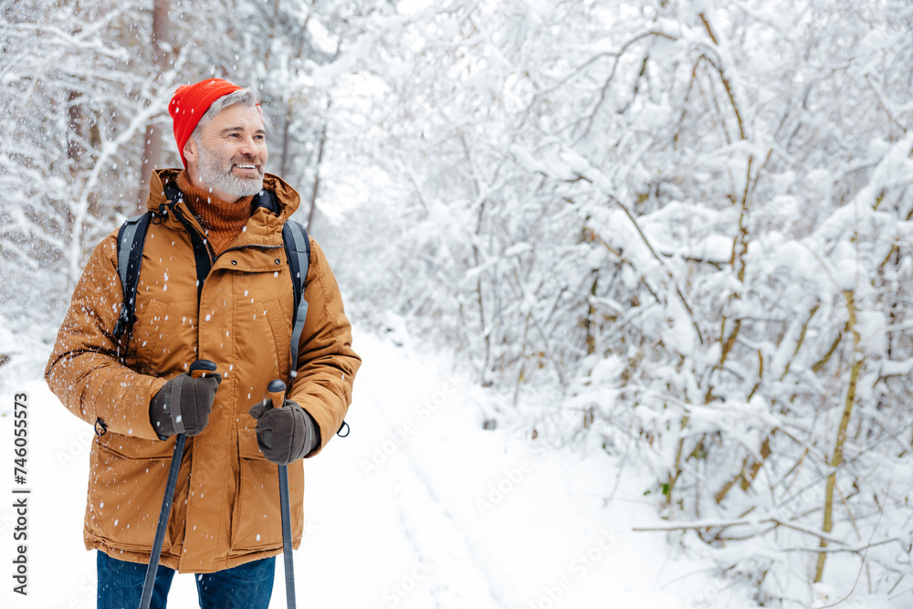 Fototapeta premium Mature caucasian man in red hat on a snowy background looking contented