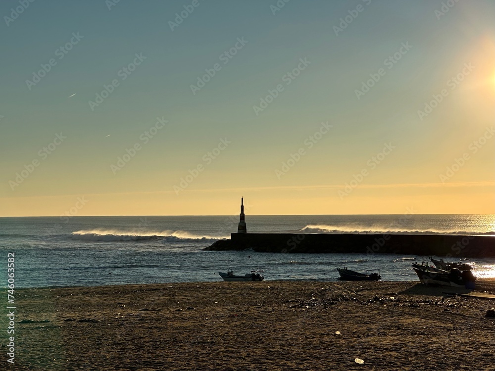 Sunset over the Atlantic ocean beach with the fishing boats and the lighthouse in Aguda, Vila Nova de Gaia, Porto, Portugal, December 2022 Sunset over the Atlantic ocean beach with the fishing boats and the lighthouse in Aguda, Vila Nova de Gaia, Porto, Portugal, December 2022
