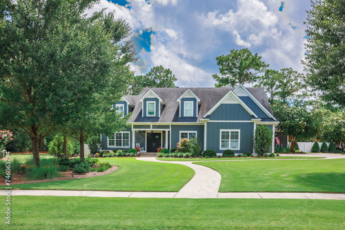 A large blue craftsman new construction house with a landscaped yard and leading pathway sidewalk photo