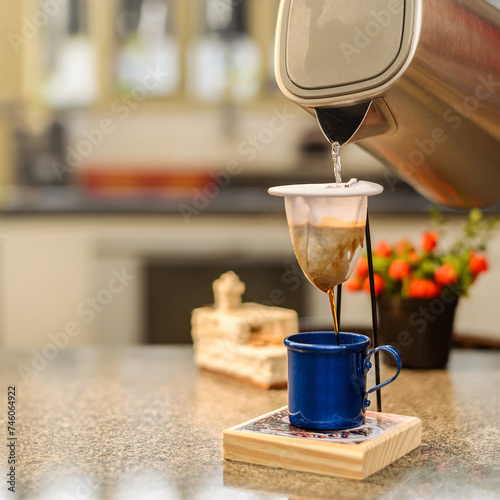 Pouring hot water into a cloth coffee strainer. Making an individual portion of black coffee.