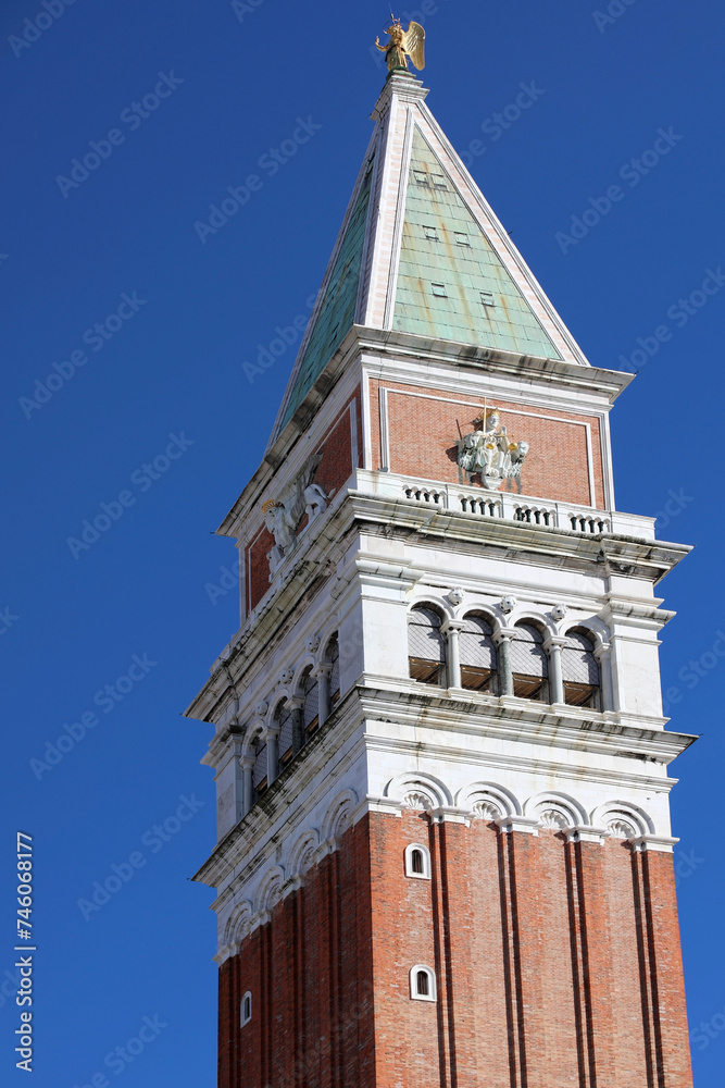 tip of the tall bell tower of Saint Mark of Venice in Italy with blue sky