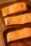 raw salmon fillets on a wooden plate