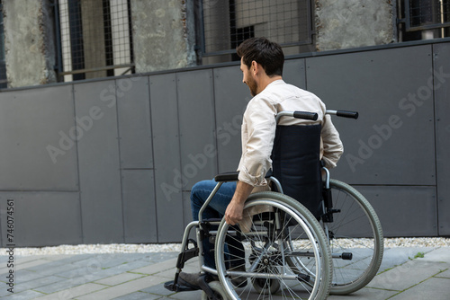 Dark-haired young caucasian man riding a wheelchair