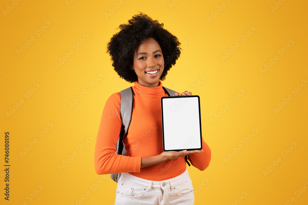 Friendly young woman with a natural afro hairstyle presents a blank tablet screen with a smile Friendly young woman with a natural afro hairstyle presents a blank tablet screen with a smile