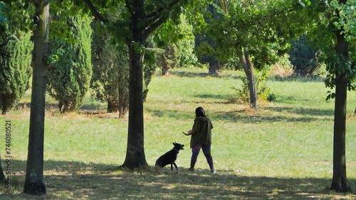 a woman playing with her dog on a lawn outdoors in Autumn Park