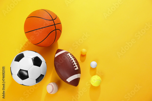 Many different sports balls on yellow background  flat lay. Space for text