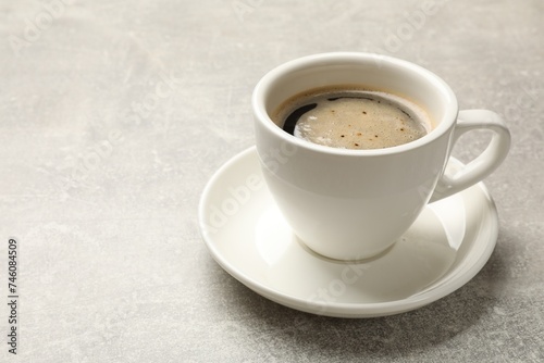 Cup of aromatic coffee on light grey table, closeup. Space for text