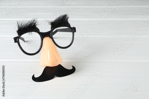 Funny mask with fake mustache, nose and glasses on white wooden background. Space for text