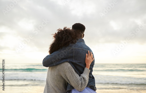 Loving multiethnic couple looking out at the ocean from a beach