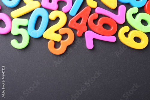 Colorful numbers on dark gray background, flat lay. Space for text