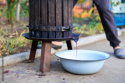 Homemade Fer grape juice for wine production flows from a press into a basin. Background