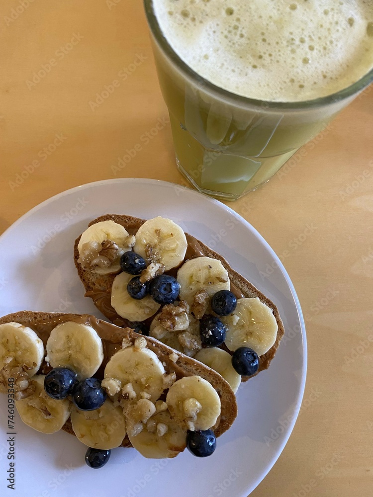 American breakfast with toast, banana, blueberries, maple syrup, nuts and green smoothie