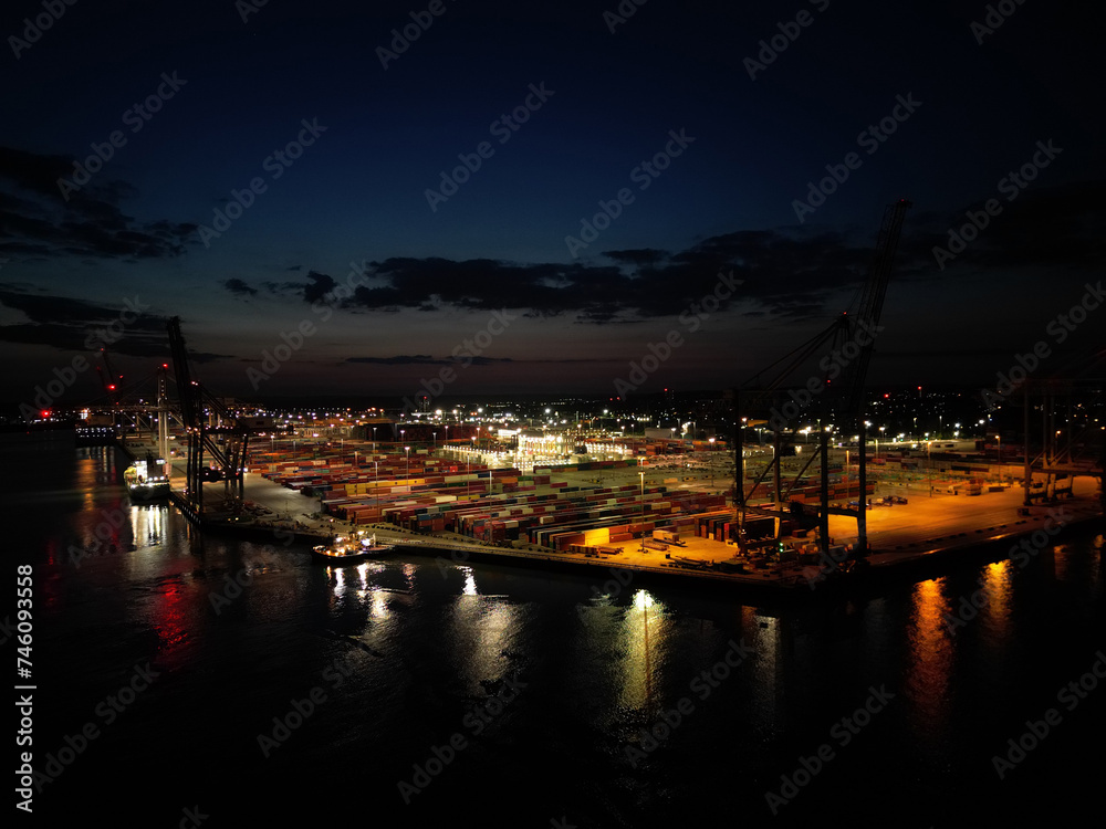 Aerial panoramic view of illuminated Southampton container terminal at dusk. Lights reflection on the sea.