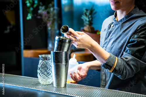 barman prepara un cocktail de piña colada con hoja de piña en un vaso decorado sobre la barra de un cocktail bar exclusivo por la noche en ambiente de fiesta, camarera close up