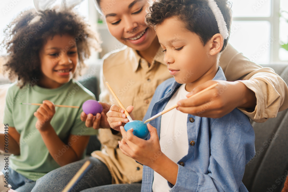 Portrait happy African American family decoration and painting Easter eggs at home. Smiling mother and kids preparation for Easter together. Holiday activity concept Portrait happy African American family decoration and painting Easter eggs at home. Smiling mother and kids preparation for Easter together. Holiday activity concept