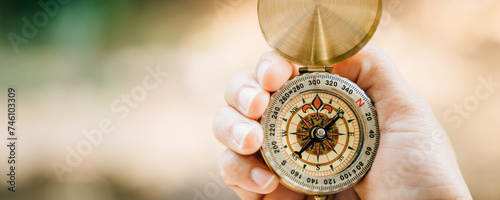 In a lush forest a hand holds a compass conveying themes of guidance and exploration. With room for text this image relates to travel lifestyle and effective business planning and success.